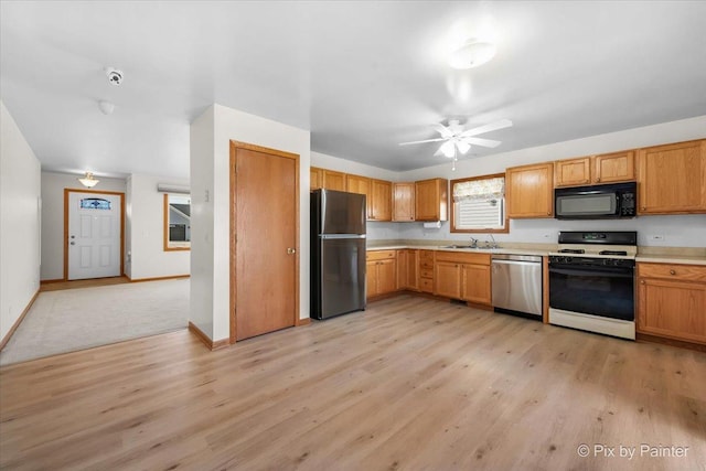 kitchen featuring light wood-style flooring, a sink, ceiling fan, light countertops, and stainless steel appliances