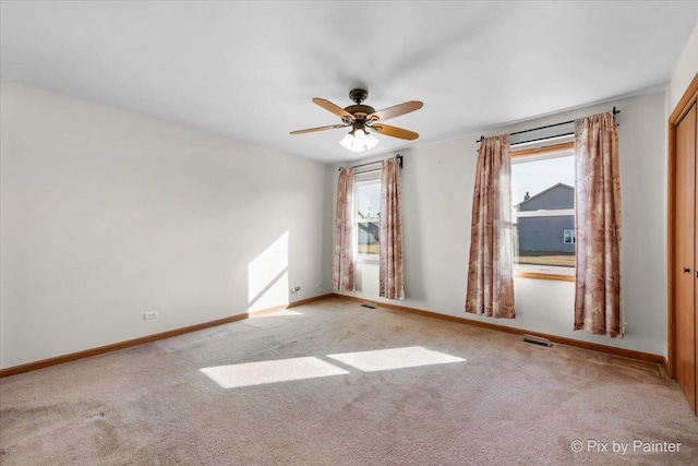 empty room with a healthy amount of sunlight, baseboards, and light carpet