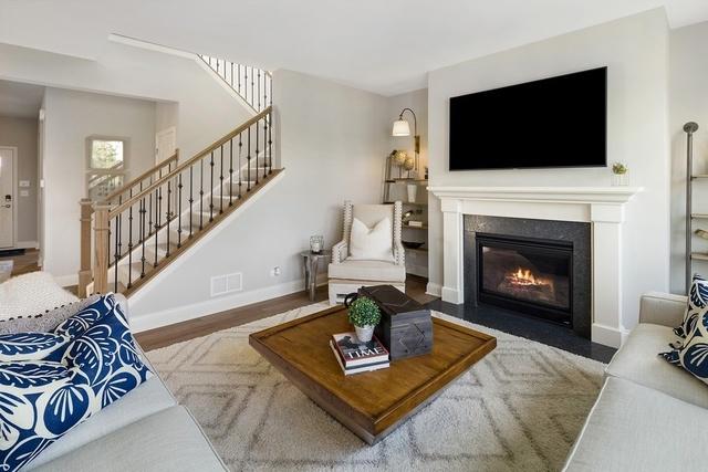 12595 Skeels St, Huntley, IL 60142 - living room with visible vents, baseboards, stairway, a fireplace with flush hearth, and wood finished floors