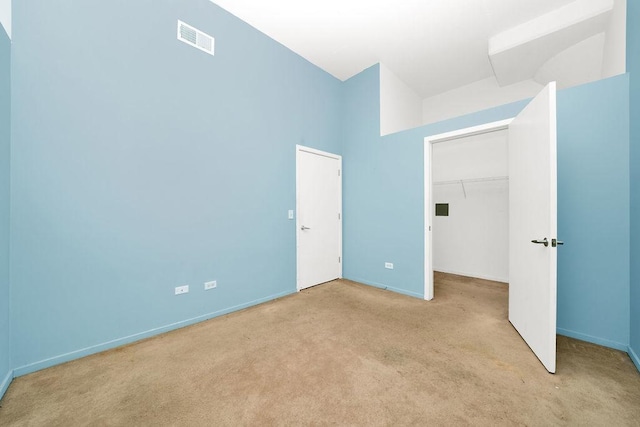 unfurnished bedroom with visible vents, a walk in closet, baseboards, carpet flooring, and a closet