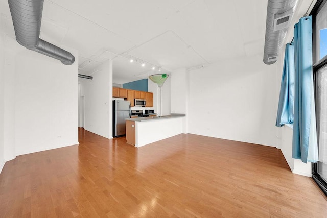 unfurnished living room with wood finished floors and rail lighting