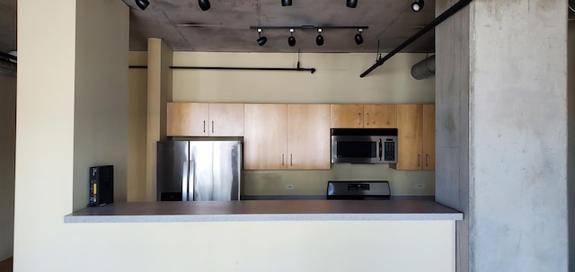 kitchen featuring a peninsula, track lighting, appliances with stainless steel finishes, and light brown cabinetry