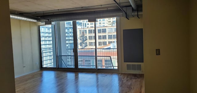 interior space featuring floor to ceiling windows, wood finished floors, and visible vents