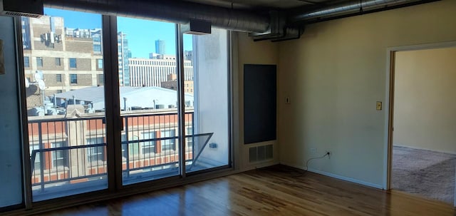 empty room featuring a city view, visible vents, and wood finished floors