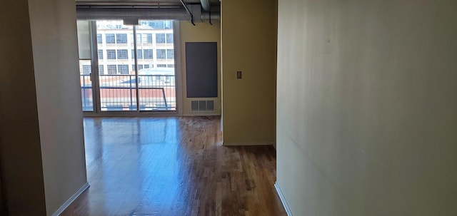 hallway with visible vents, baseboards, and wood finished floors