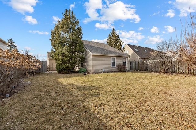 back of property featuring a yard, fence, and roof with shingles