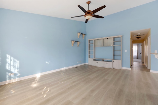 unfurnished living room featuring a high ceiling, baseboards, light wood-type flooring, and ceiling fan