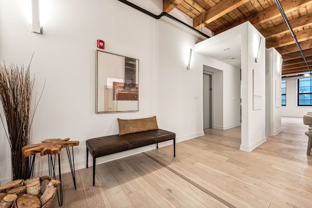 living area with light wood-type flooring, beam ceiling, baseboards, and wooden ceiling