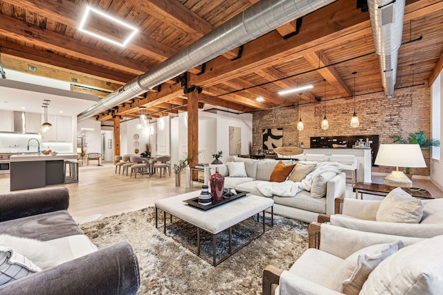 living room featuring light wood-style flooring, beam ceiling, wood ceiling, and brick wall