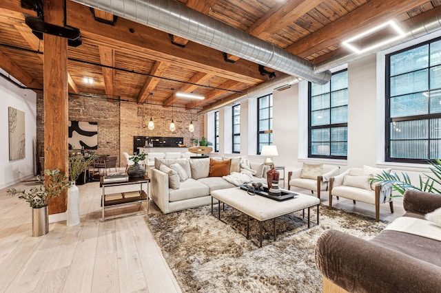 living room featuring beam ceiling, brick wall, wooden ceiling, and light wood-style floors