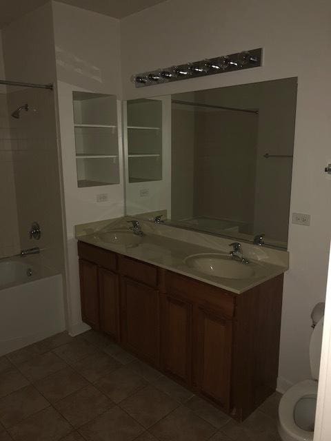 bathroom featuring double vanity, tub / shower combination, tile patterned floors, and a sink