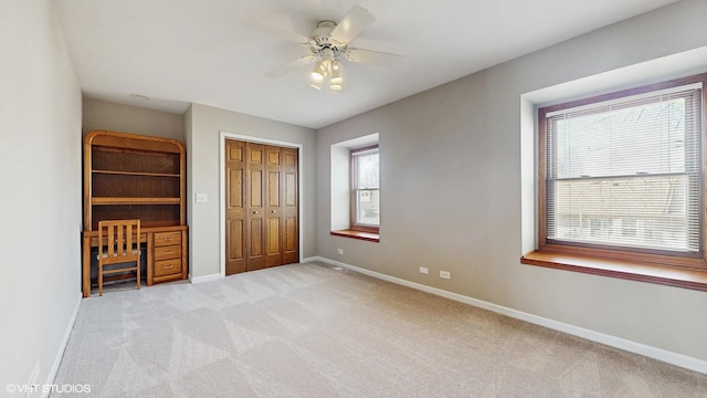 unfurnished bedroom with light carpet, a closet, baseboards, and a ceiling fan