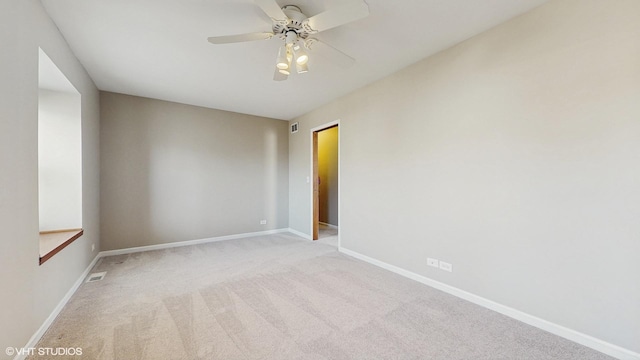 carpeted spare room featuring visible vents, baseboards, and ceiling fan