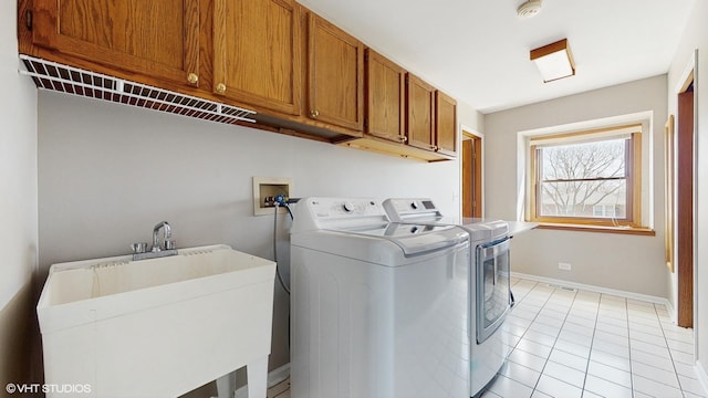 laundry room featuring washing machine and clothes dryer, baseboards, light tile patterned flooring, cabinet space, and a sink