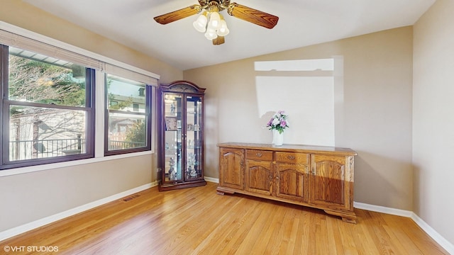 interior space featuring light wood-style flooring, a ceiling fan, and baseboards