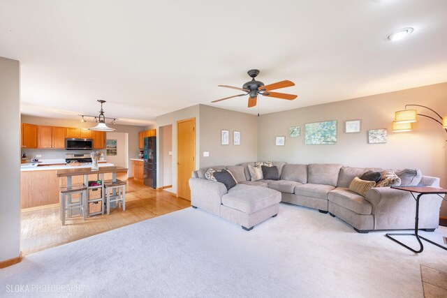 living room with light colored carpet and a ceiling fan
