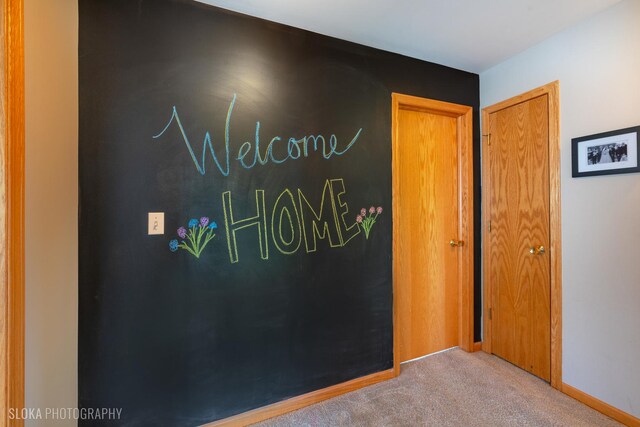 hallway featuring carpet and baseboards