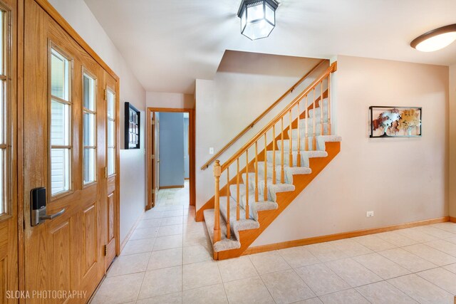 foyer with stairway, light tile patterned floors, and baseboards
