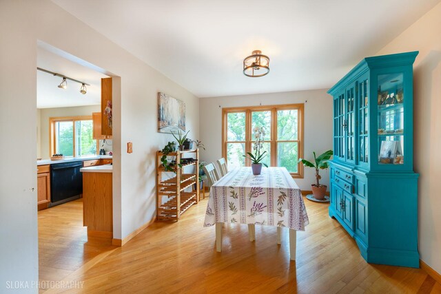 dining room with light wood finished floors, track lighting, and baseboards
