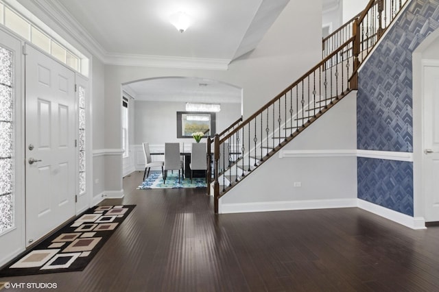 foyer entrance featuring arched walkways, wallpapered walls, and baseboards