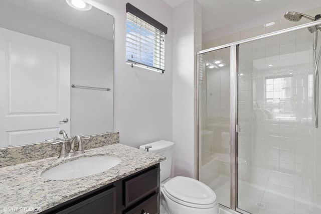 full bathroom featuring vanity, a shower stall, and toilet
