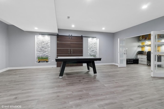recreation room with recessed lighting, light wood-type flooring, baseboards, and a barn door