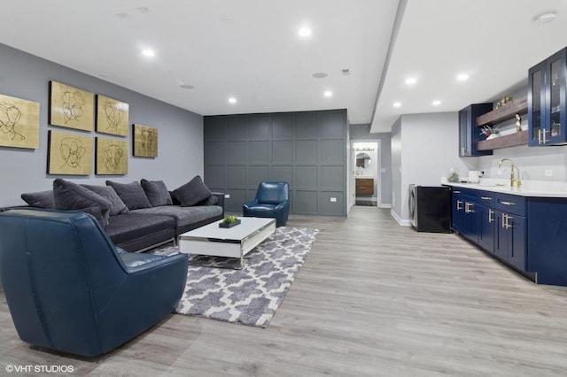 living room with baseboards, wet bar, light wood finished floors, and recessed lighting