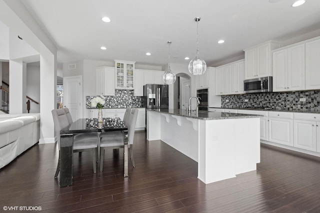 kitchen with tasteful backsplash, dark stone countertops, stainless steel appliances, and recessed lighting
