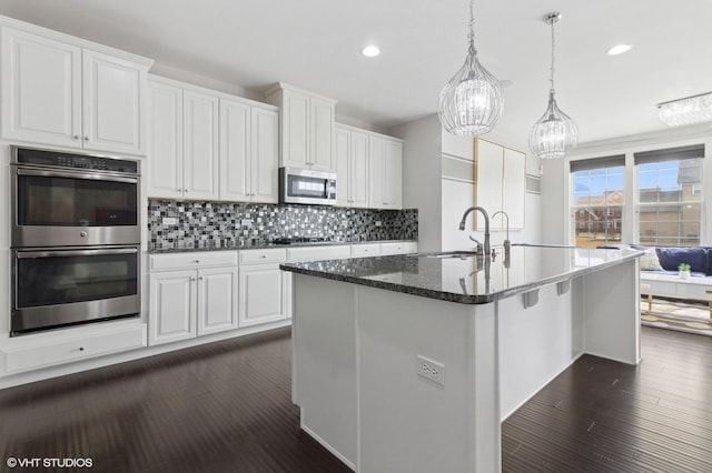kitchen with white cabinets, decorative backsplash, a sink, and appliances with stainless steel finishes