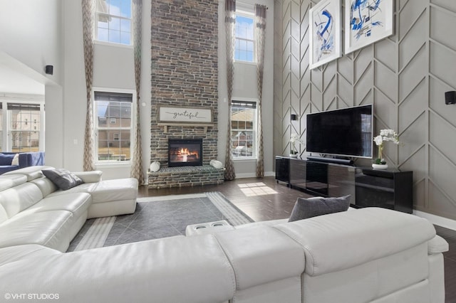 living room with baseboards, a brick fireplace, and a high ceiling