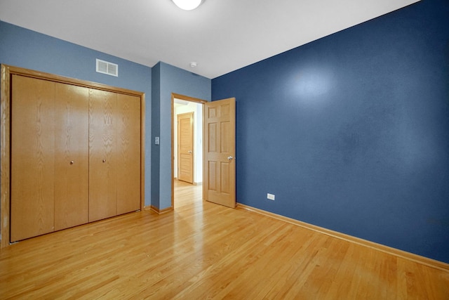 unfurnished bedroom featuring visible vents, baseboards, a closet, and light wood finished floors