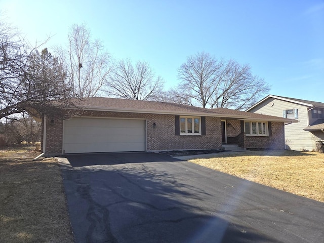 single story home featuring aphalt driveway, an attached garage, a front lawn, and brick siding