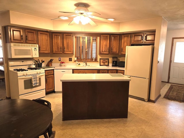 kitchen featuring a sink, a kitchen island, white appliances, light countertops, and ceiling fan