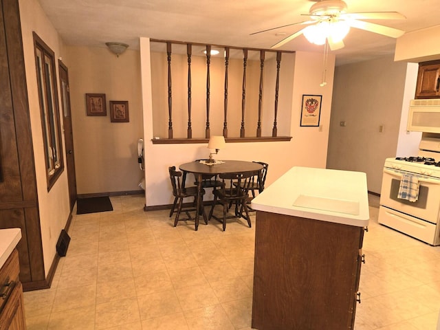 kitchen featuring white appliances, a ceiling fan, light countertops, and baseboards