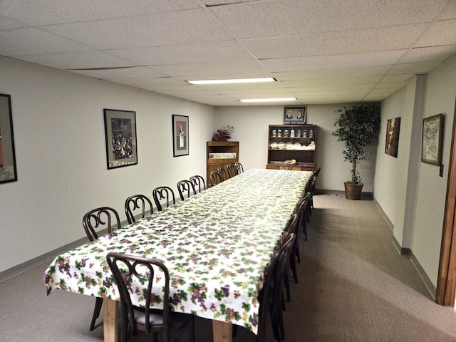 dining space with baseboards, a drop ceiling, and carpet floors