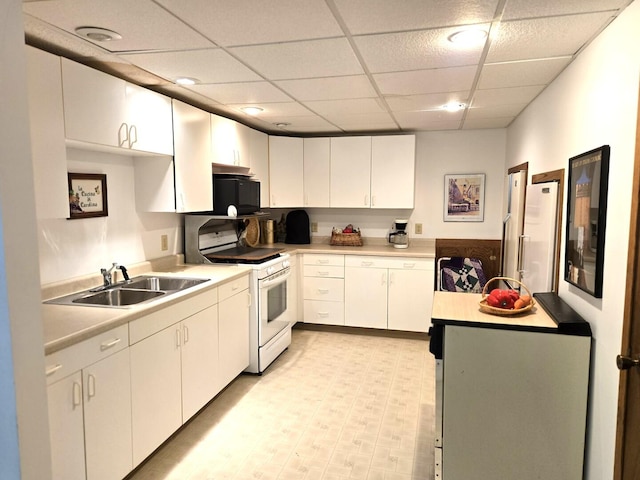 kitchen with light countertops, white gas range, black microwave, and a sink