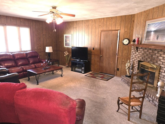 living area with ceiling fan, carpet, a brick fireplace, and wood walls