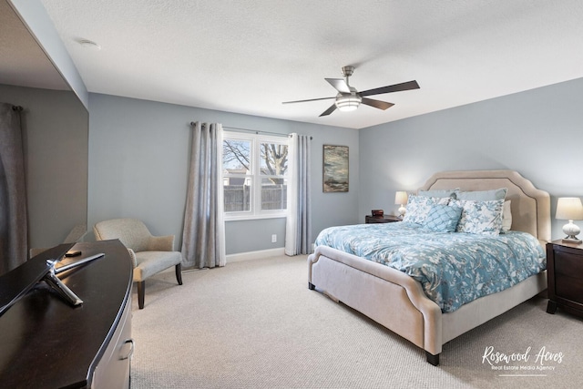 bedroom featuring light colored carpet, a textured ceiling, baseboards, and a ceiling fan