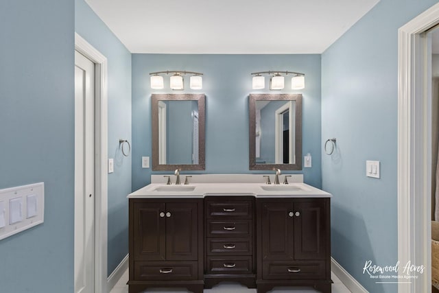 full bathroom featuring a sink, baseboards, and double vanity