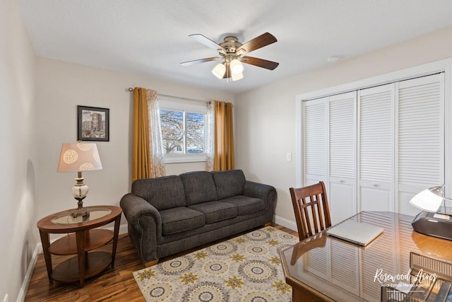 living area featuring ceiling fan, baseboards, and wood finished floors