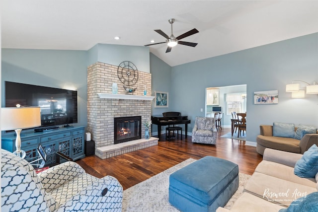 living area featuring lofted ceiling, a ceiling fan, wood finished floors, baseboards, and a brick fireplace