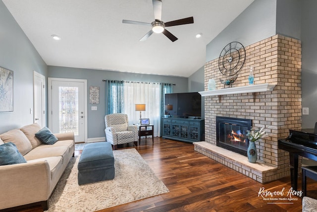 living room featuring lofted ceiling, a ceiling fan, wood finished floors, baseboards, and a brick fireplace