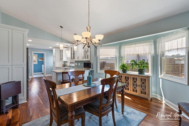 dining space with baseboards, lofted ceiling, dark wood finished floors, and a chandelier