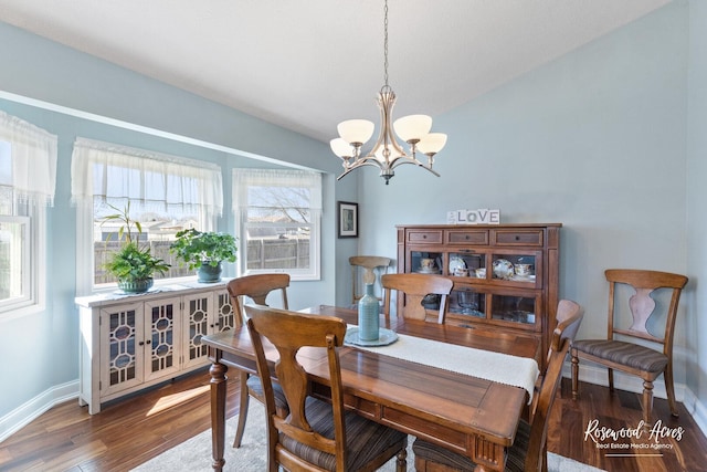 dining space with a notable chandelier, lofted ceiling, baseboards, and wood finished floors