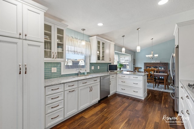 kitchen featuring a sink, dark wood-style floors, appliances with stainless steel finishes, a peninsula, and white cabinets