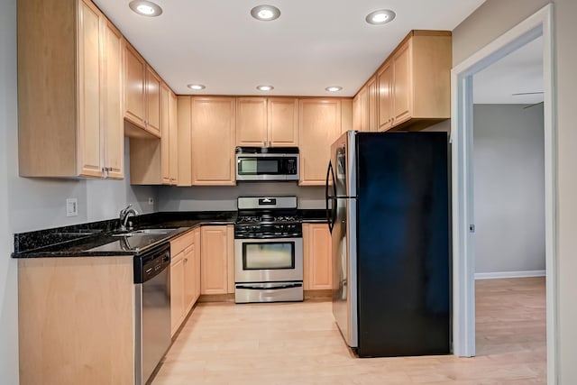kitchen featuring stainless steel appliances, light brown cabinetry, a sink, recessed lighting, and light wood-type flooring
