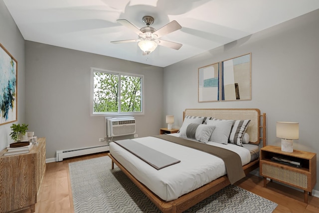 bedroom with baseboard heating, a wall mounted air conditioner, light wood-style floors, ceiling fan, and baseboards