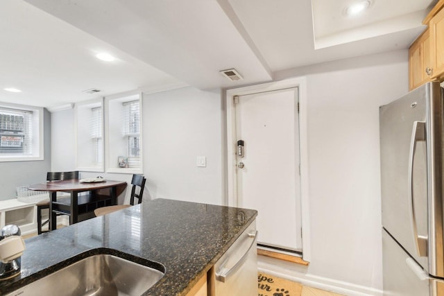 kitchen with dark stone countertops, recessed lighting, visible vents, and stainless steel refrigerator