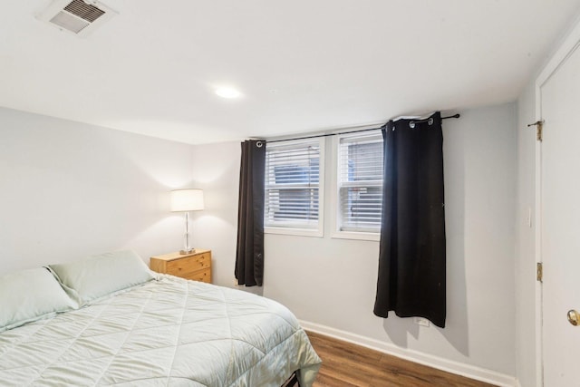 bedroom with visible vents, baseboards, and wood finished floors