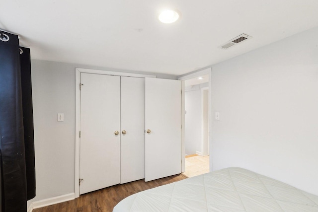 bedroom featuring wood finished floors, visible vents, and a closet